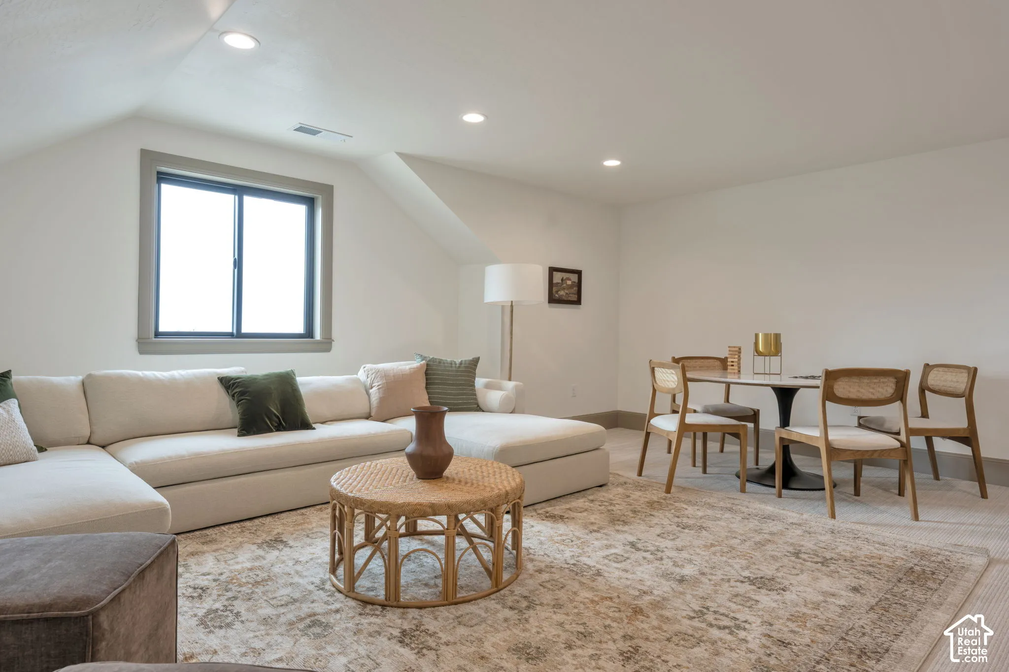 Recessed lighting, sloped ceiling, window with dark trim, light-toned walls, and wood-finish flooring