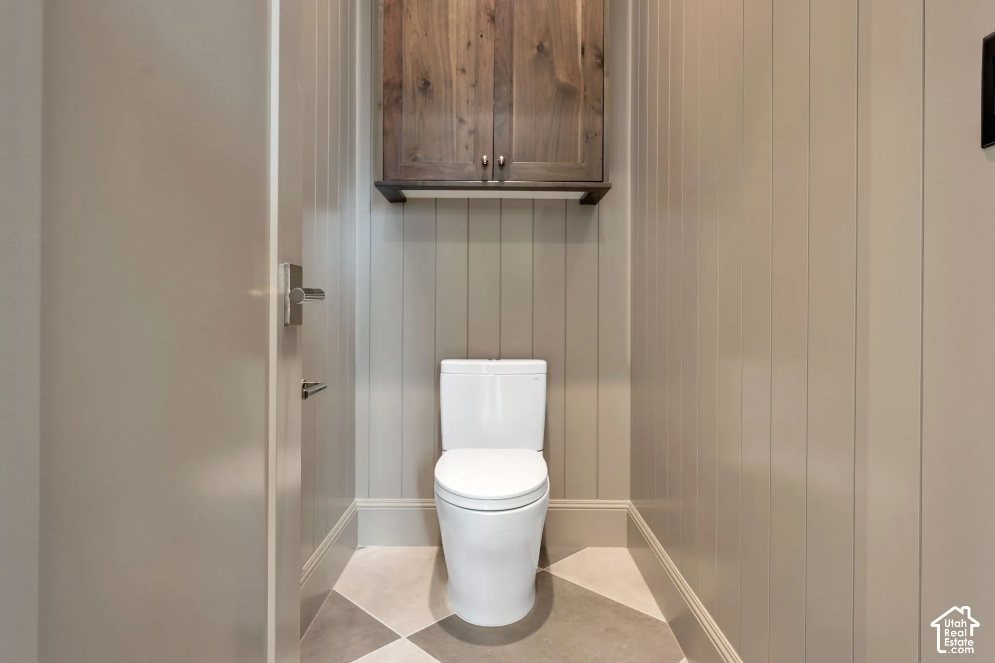 Vertical paneled wainscoting, two-tone checkered flooring, and a wall-mounted wood-finish cabinet