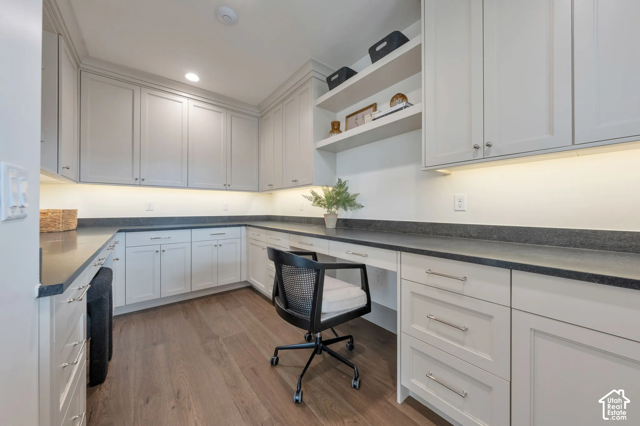 Extensive built-in cabinetry, dark countertops, wood-finish flooring, recessed lighting, and integrated shelving