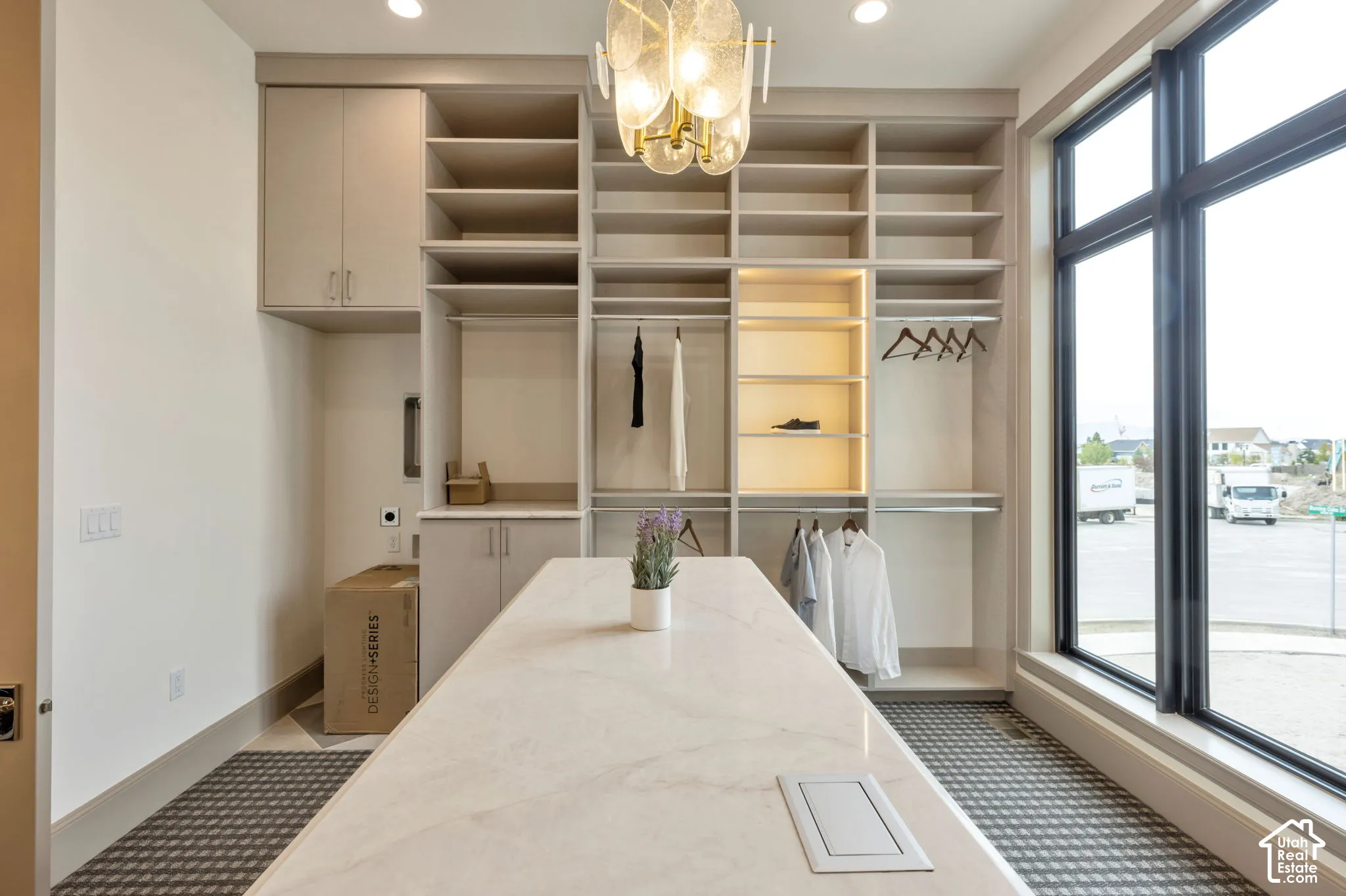 Built-in custom cabinetry, integrated shelving, an expansive center island with a stone surface, and a large multi-pane window