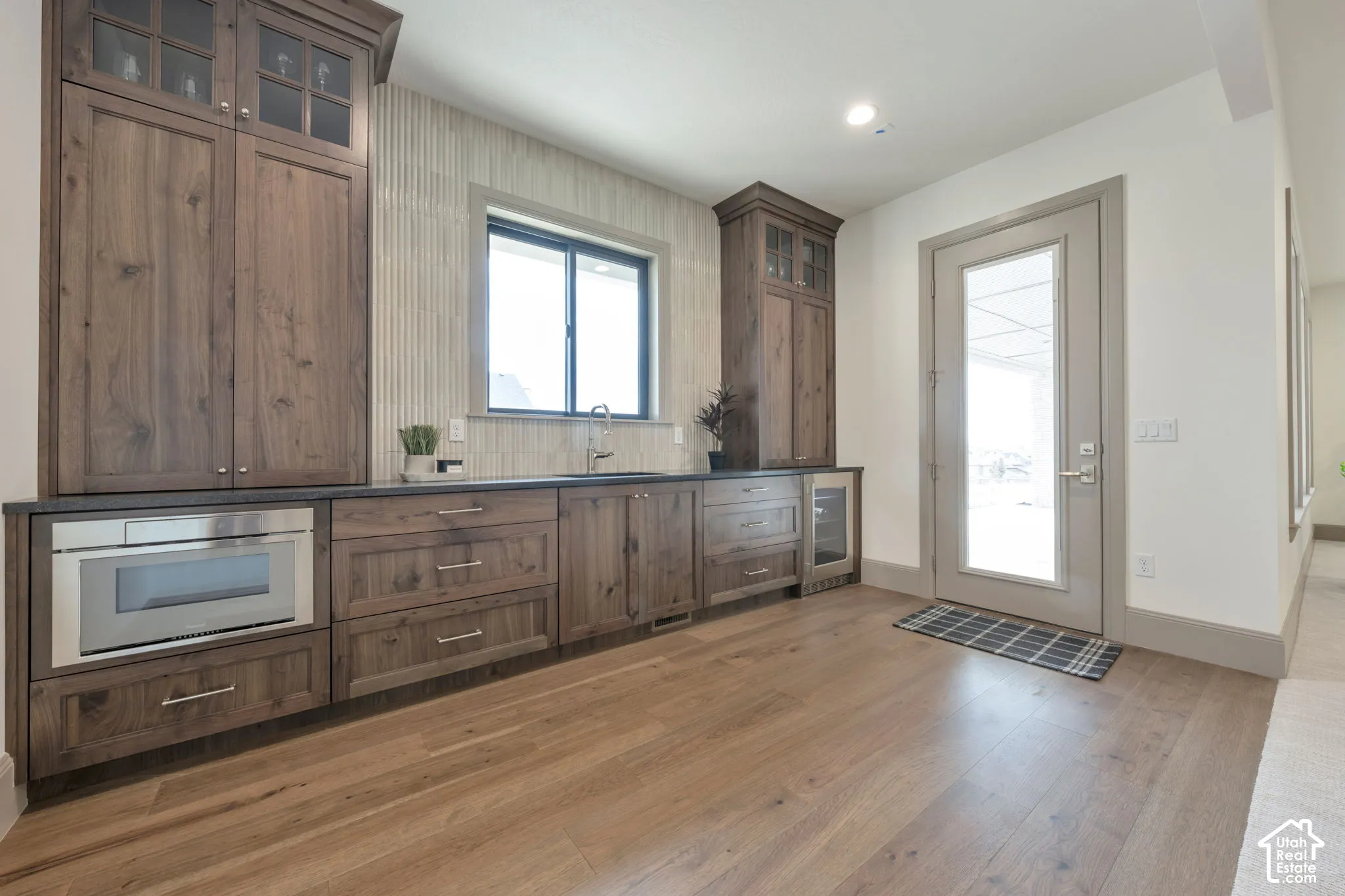Wood-finish flooring, full-light exterior door, built-in cabinetry with glass inserts, integrated microwave, and a beverage cooler