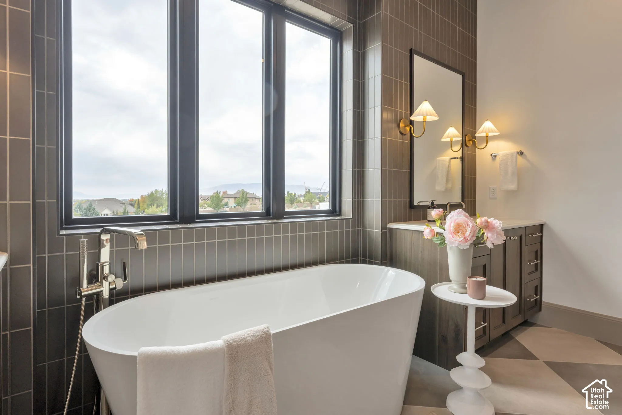Freestanding tub with a floor-mounted polished chrome faucet, surrounded by tiled walls