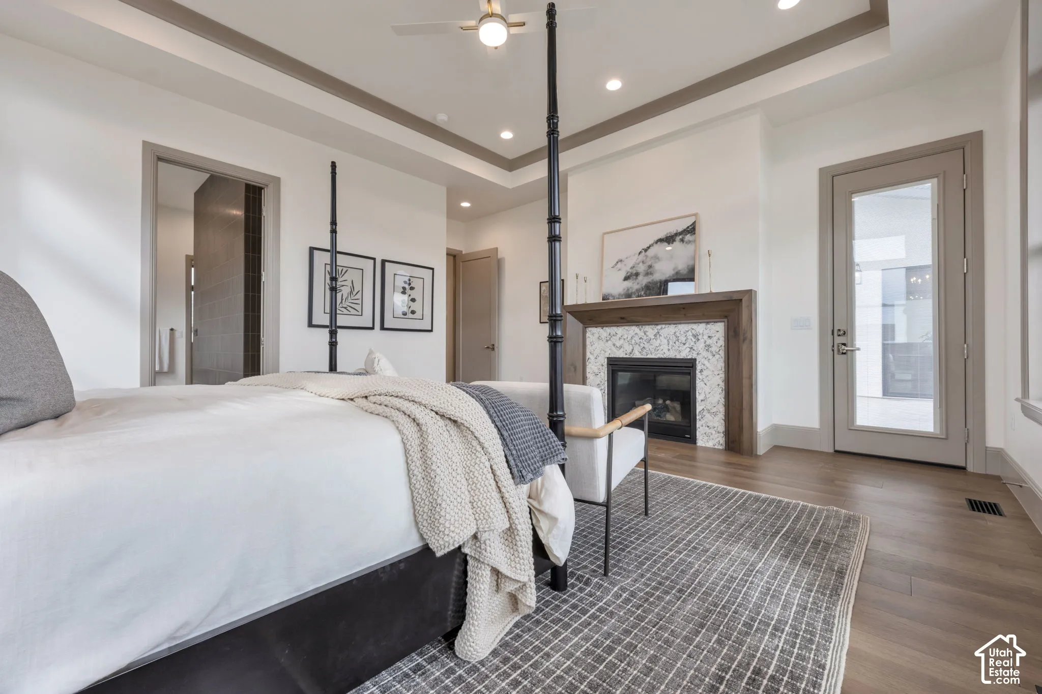 Wood-finish flooring, recessed lighting, ceiling fan, fireplace with a tiled surround and wood mantel, and a glass-paneled door