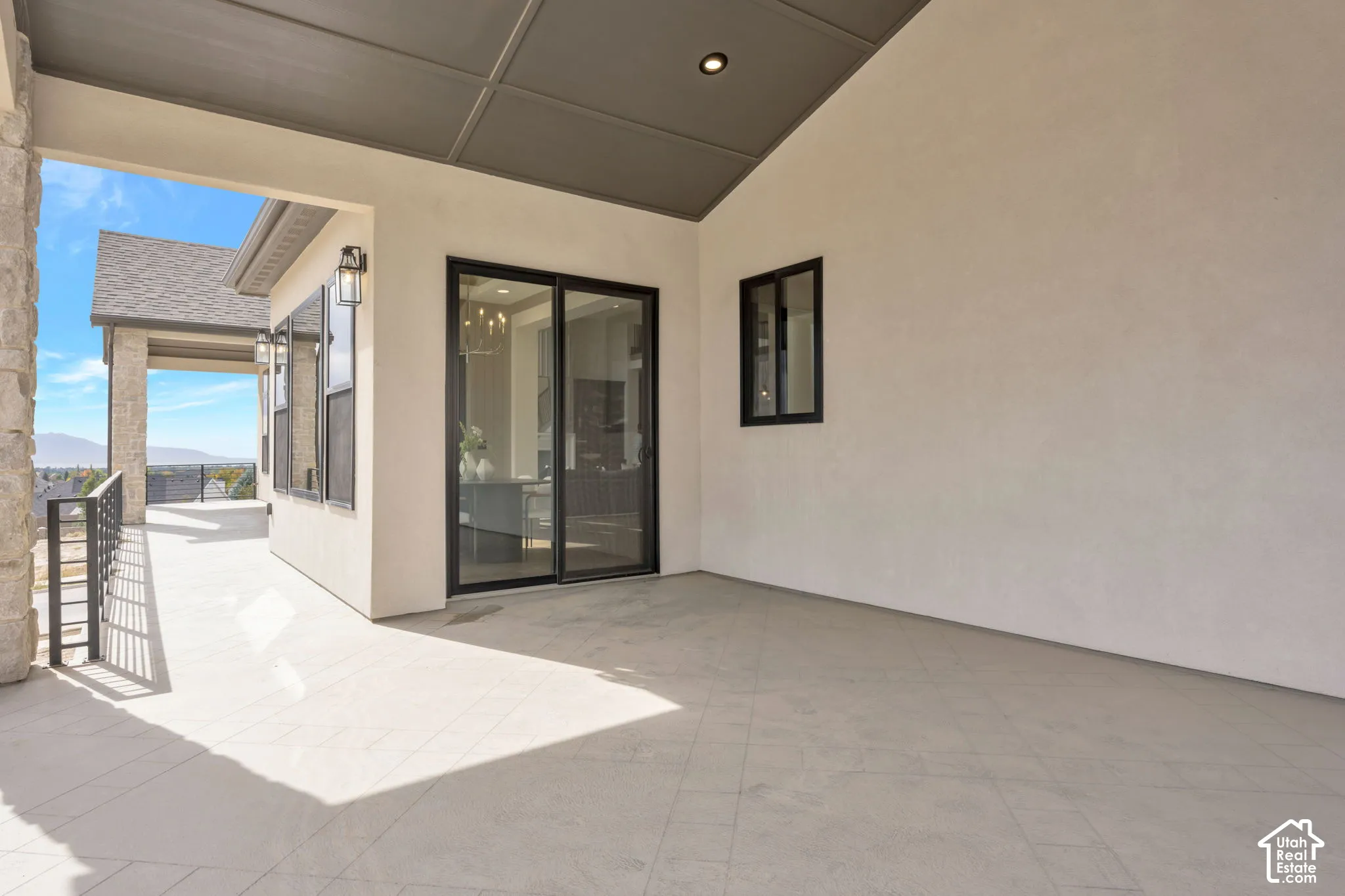 Covered patio with a coffered ceiling, tile flooring, and black-framed sliding glass doors