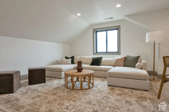 Attic space featuring an angled ceiling, recessed lighting, and a framed window
