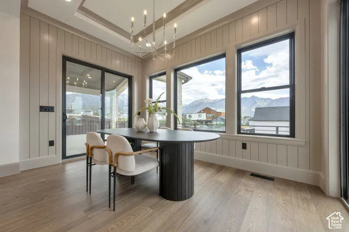 Tray ceiling with recessed lighting and a chandelier, light wood-finish flooring, and board and batten wall paneling