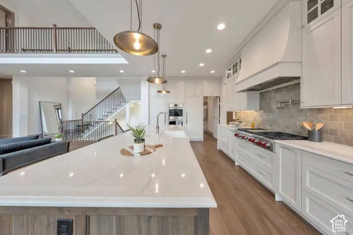 Spacious kitchen featuring a large island with a countertop, wood-finish flooring, and white cabinetry