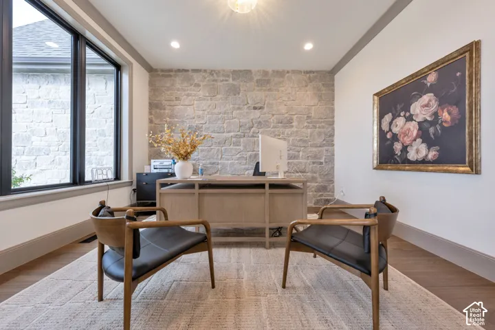 Stone accent wall, recessed lighting, wood-finish flooring, black trim windows, built-in desk