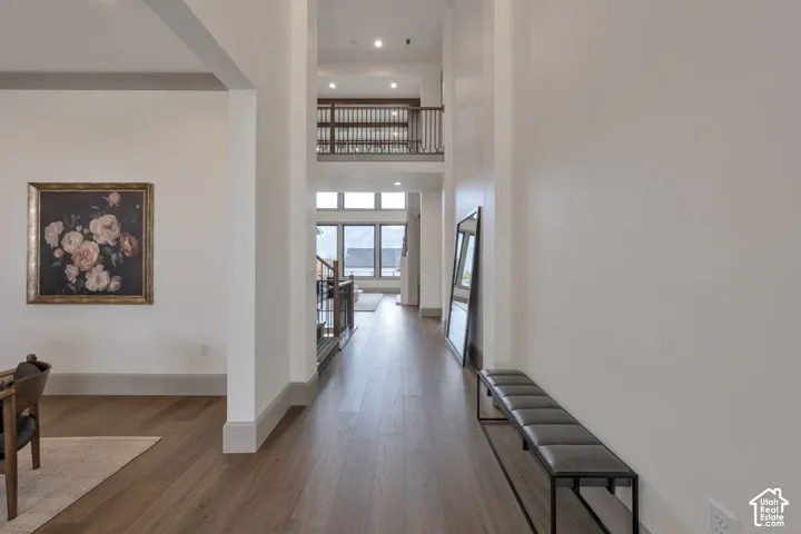 Wood-finish flooring throughout, soaring ceilings, upper-level balcony with wood and metal railings, and extensive window placement