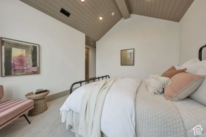 Vaulted wood-paneled ceiling with exposed beams, recessed lighting, wall-to-wall carpeting, and a black metal bed frame