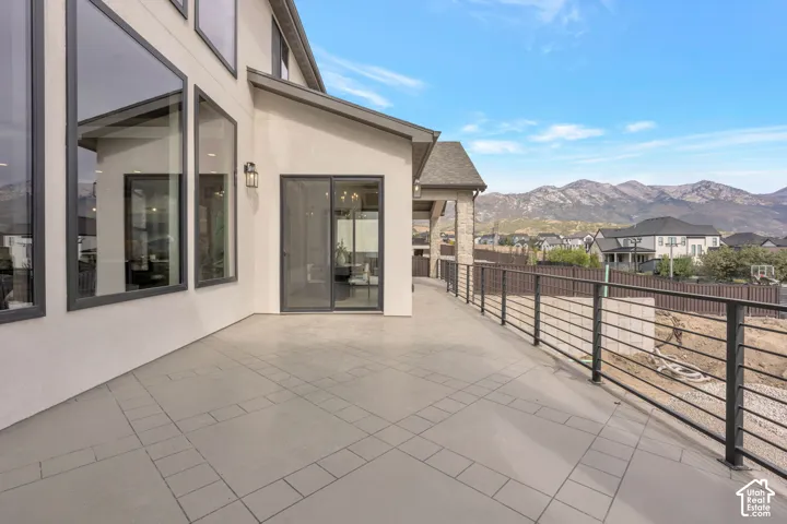 Expansive outdoor patio with patterned tile flooring, contemporary horizontal metal railings, and a sliding glass door