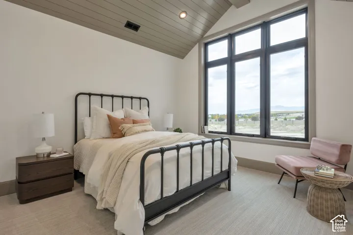 Vaulted ceiling with wood-finish paneling, large multi-pane windows with dark frames, and light-toned carpeting