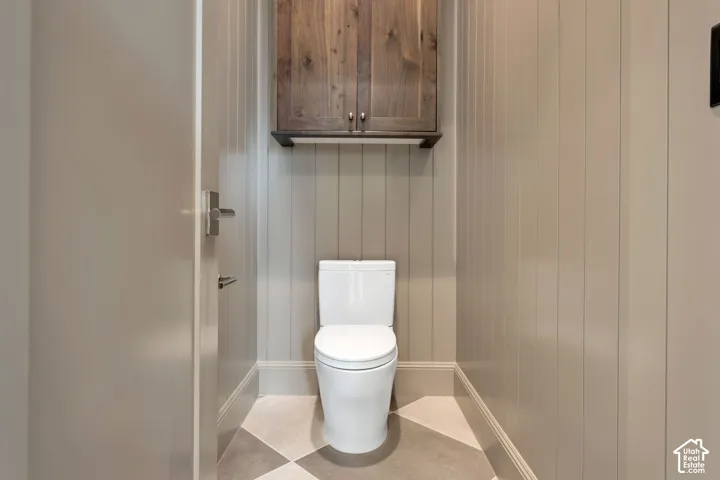 Vertical paneled wainscoting, two-tone checkered flooring, and a wall-mounted wood-finish cabinet