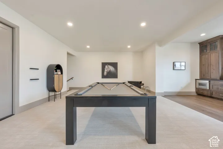 Recessed lighting illuminates the expansive carpeted area, complemented by wood-finish flooring
