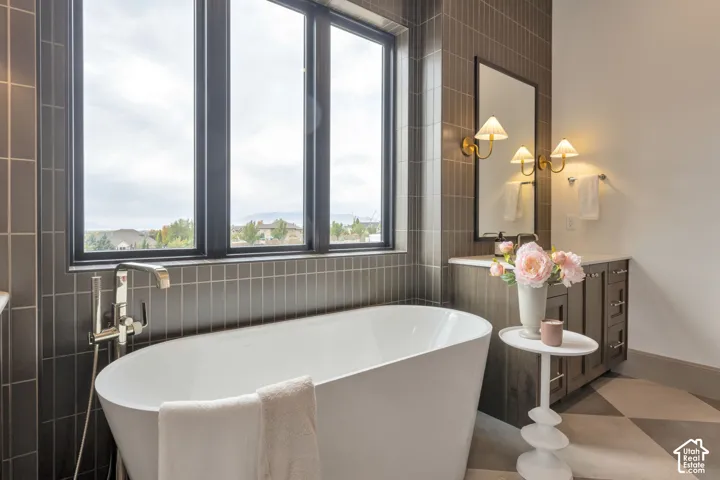 Freestanding tub with a floor-mounted polished chrome faucet, surrounded by tiled walls