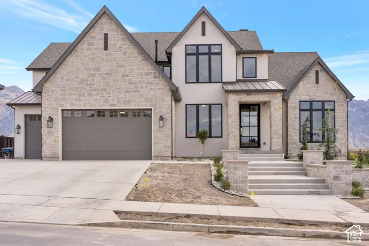 Stone and stucco exterior with multiple gables and a dark gray roof