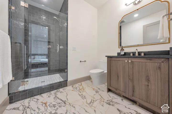 Walk-in shower with glass enclosure, wood-finish vanity with dark countertop, large decorative mirror, and marble-look flooring