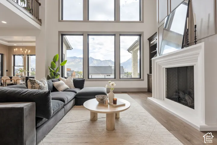 Two-story living area featuring a prominent fireplace, high ceilings, large windows, and light wood-finish flooring