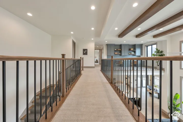 Expansive upper-level hallway with carpet flooring, recessed lighting, and a wood and metal baluster railing system