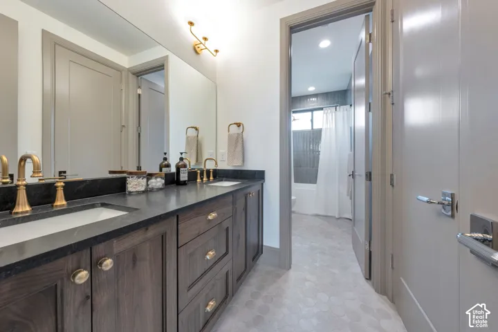 Double vanity with dark wood-finish cabinetry, a dark countertop, and brass fixtures