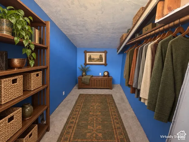 Built-in shelving unit, integrated clothing rods, textured wall finish, wood-finish flooring, and built-in storage chest