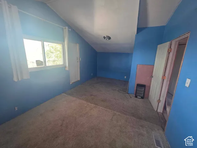 Sloped ceiling room featuring a window and an interior door