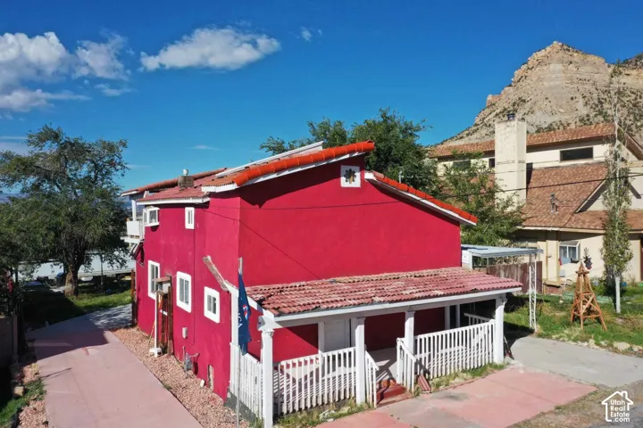 Red stucco exterior with white trim windows and a covered front porch featuring white railings