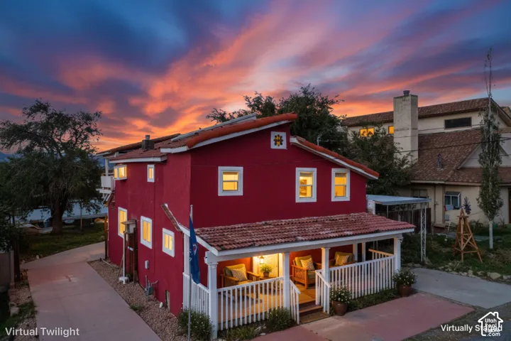 Red exterior with white trim windows and a covered front porch featuring white railing