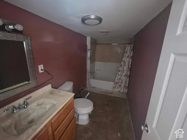 Vanity with wood-finish cabinetry and integrated sink, mirrored wall-mounted vanity light fixture, and a built-in bathtub with tiled surround