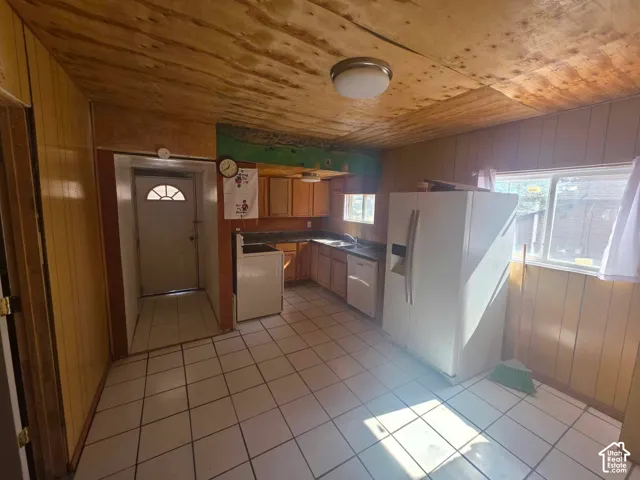 Kitchen with wood-finish paneling, white floor tiling, and a built-in kitchen sink