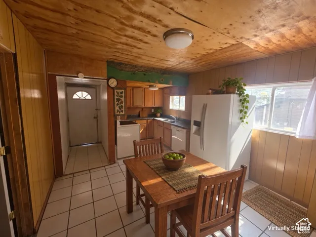 Kitchen with wood-finish ceiling, light wood-finish paneling, and white tile flooring