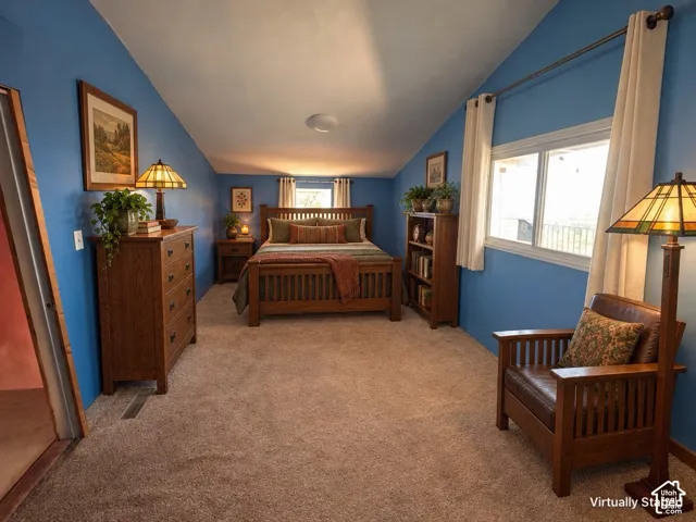 Sloped ceiling architecture with recessed lighting, wall-to-wall carpeting, and multiple windows