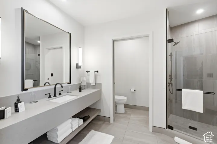 Contemporary bathroom featuring a floating vanity with integrated sink, matte black fixtures, a large framed mirror, and a glass-enclosed shower with tiled walls