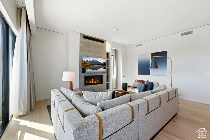 Spacious living area featuring wood-finish flooring, a built-in fireplace, and expansive windows