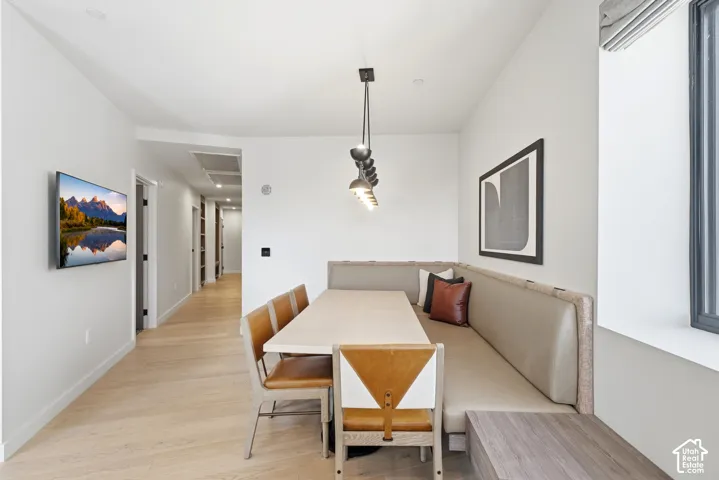 Built-in upholstered banquette seating with a light wood-finish table, complemented by pendant lighting