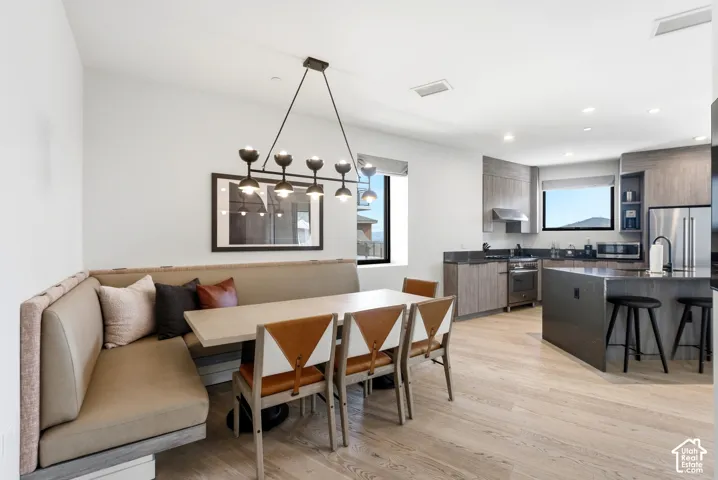 Open-concept living area featuring light wood-finish flooring, a built-in dining banquette, and a modern chandelier