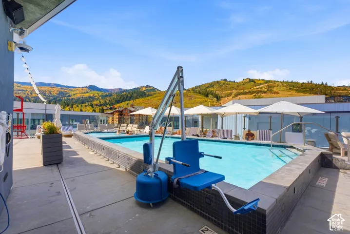 Rooftop pool deck featuring a swimming pool with integrated access, multiple lounge chairs, and sun umbrellas