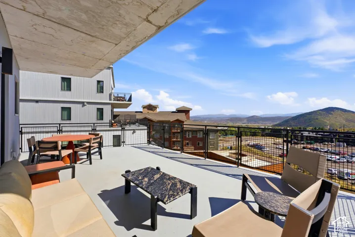 Expansive outdoor terrace with a concrete surface, metal railings, and a partial overhead covering