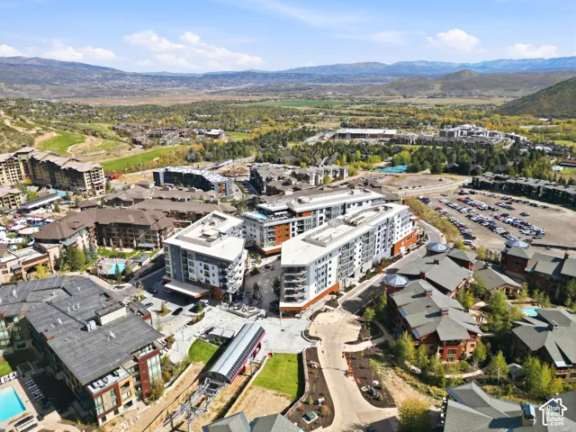 Modern multi-story buildings with balconies, surrounded by varied architectural styles, and distant mountain scenery
