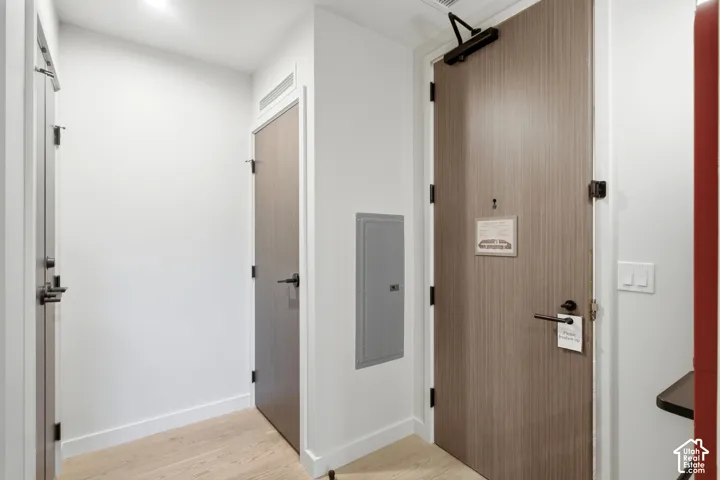 Wood-finish doors, matte black door hardware, light wood-finish flooring, recessed lighting, and a wall-mounted electrical panel