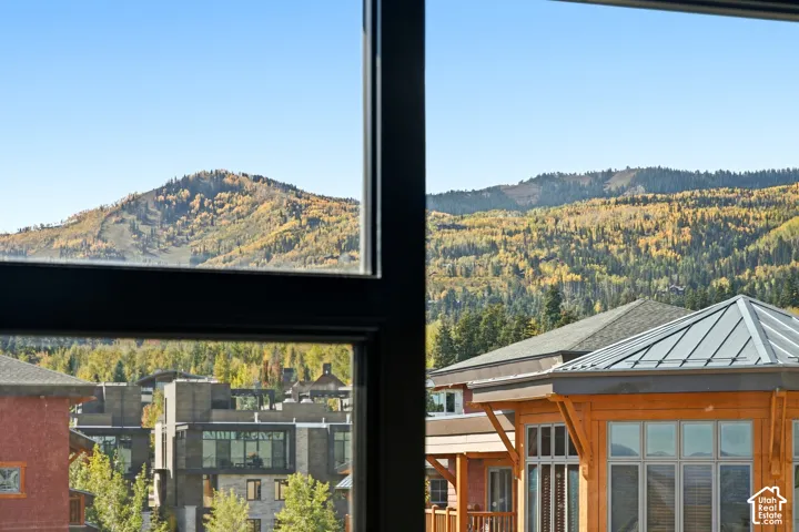 Mountain scenery with deciduous trees, clear skies, and a multi-pane window frame