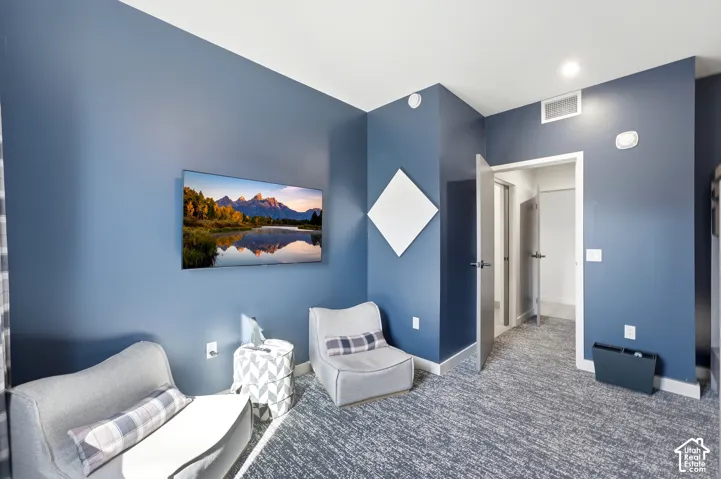 Wall-mounted television display, recessed ceiling lighting, light-colored trim, and plush carpet flooring