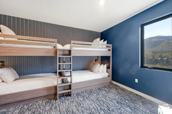Built-in bunk beds with integrated ladders, accent wall with geometric pattern, recessed lighting, and a large window with mountain scenery