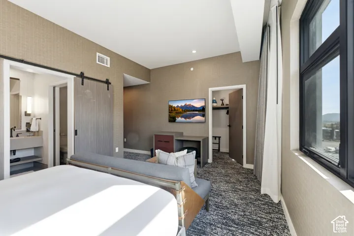 Patterned wall covering, recessed lighting, barn door entry, built-in desk, and large window with dark frame