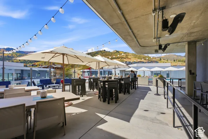 Expansive outdoor patio with concrete flooring, string lighting, and multiple umbrellas providing shade