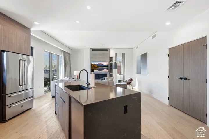 Gourmet kitchen with a large central island, undermount sink, and stainless steel French door refrigerator