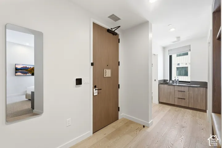 Wood-finish flooring throughout, flat panel cabinetry with dark countertops, and a window with roller shade