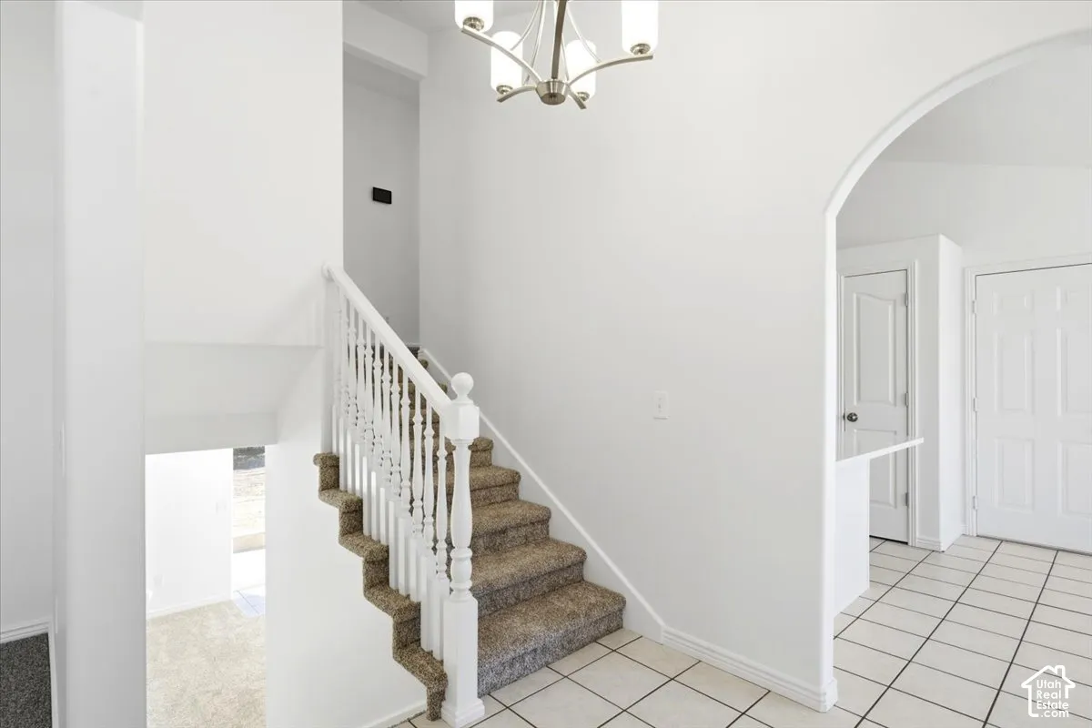 Carpeted staircase with white balusters, leading to an upper level