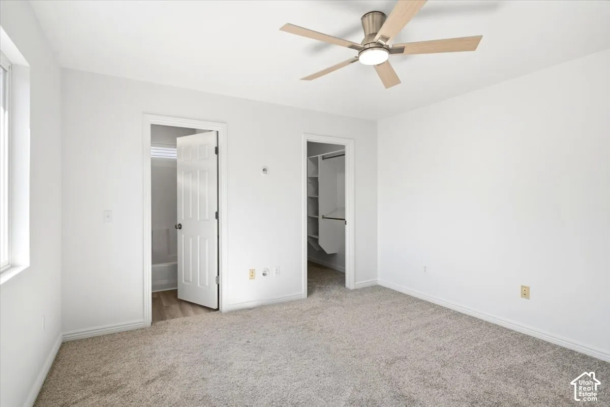 Master Bedroom with spacious bedroom with neutral carpeting, ceiling fan with brushed nickel finish, and multiple closet access points