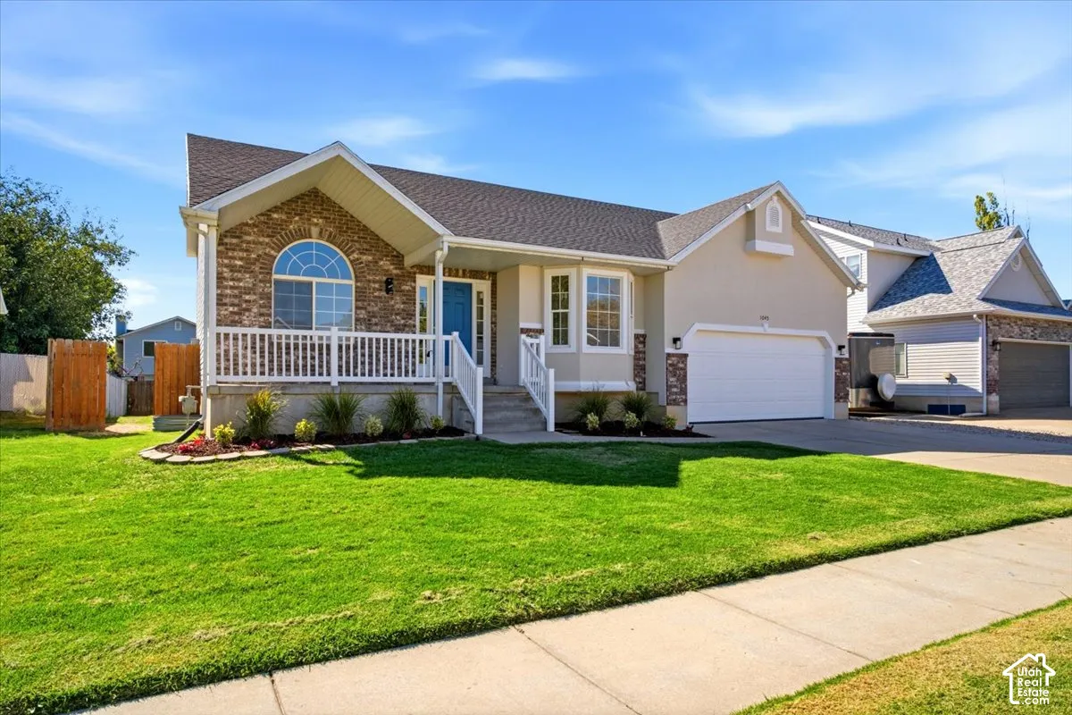 Exterior featuring brick and stucco finishes, an arched window, a covered front porch with white railing, and an attached two-car garage